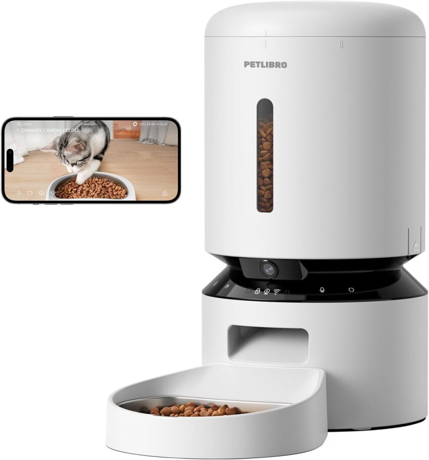 Sleek white smart pet feeder displaying kibble and camera. Smartphone shows live cat eating feed.