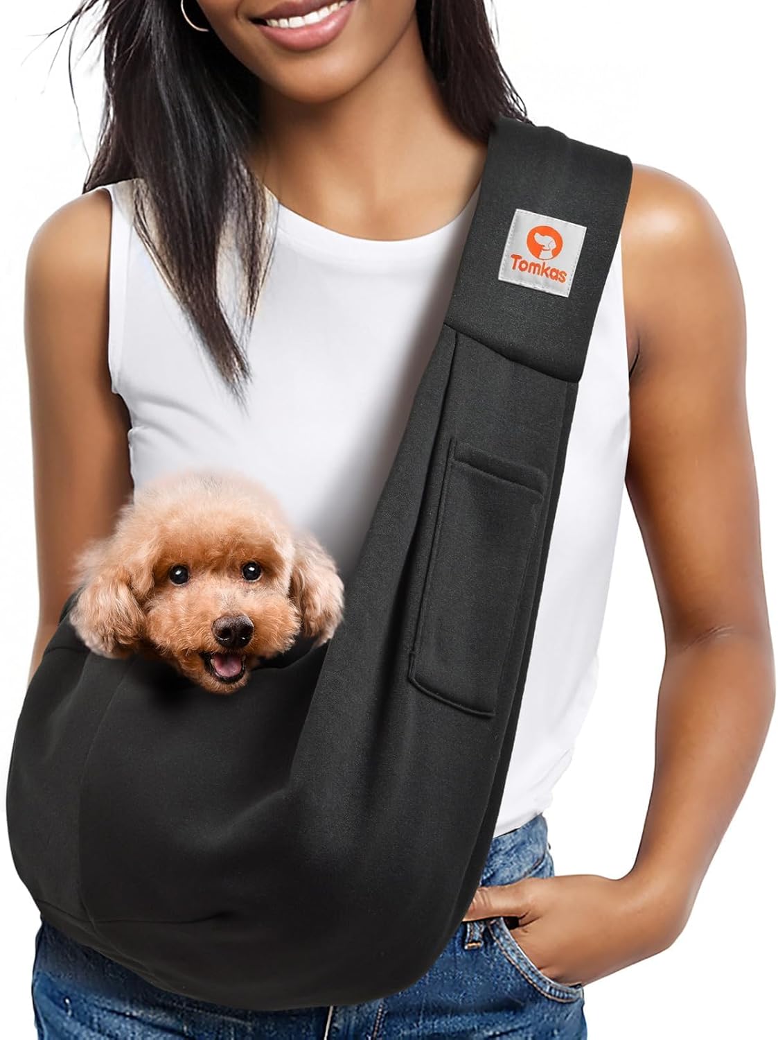 Black pet sling with small brown dog, beside folded matching pet carrier.