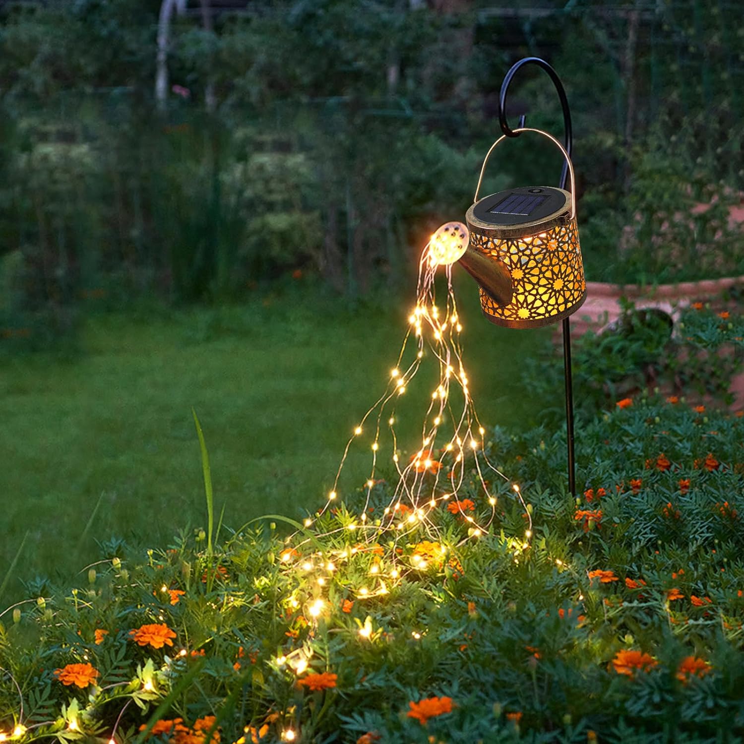 Two glowing metal solar watering cans with intricate cut-out designs on a light gray background.